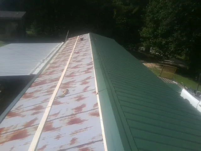 Old rusted panels beside newly installed green metal roofing — Wind Damage Roof Repair by Roofing Brothers in Mc Dermitt