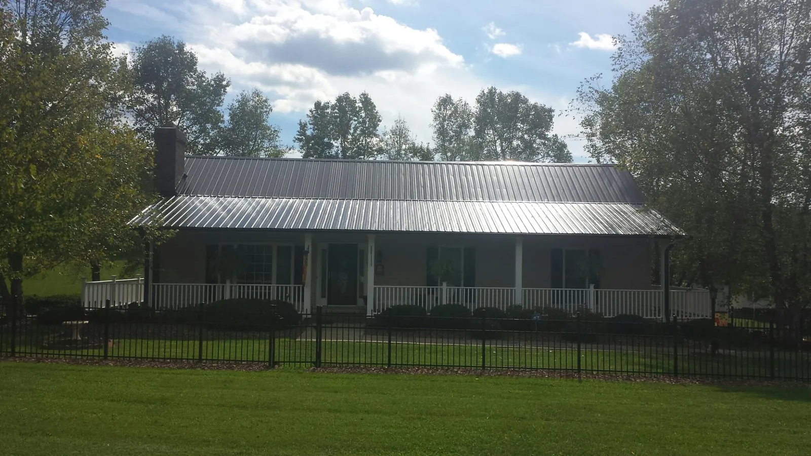 Gray metal roof on a brick ranch with a full width front porch — Gutter Guard Installation work by our crew in Mc Dermitt