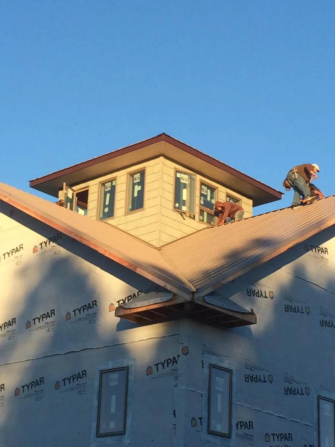 Roofers working around a rooftop cupola on a new metal roof at sunset — Roof Waterproofing in Mc Dermitt by Roofing Brothers